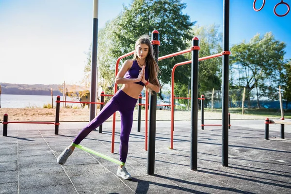 Beautiful slim girl in sport sportswear makes morning  exercise at outdoor sportsground.  Concept of good physical shape and healthy lifestyle.