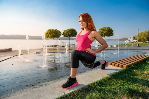 Genç bir kadın sabah erkenden bacaklarını açıyor. Açık havada çalışma saatinden önce..