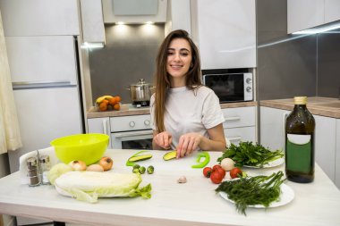 Çekici kız farklı sebzelerden ve zeytinyağlı sebzelerden oluşan bir salata hazırlıyor sağlıklı bir yaşam tarzı için.