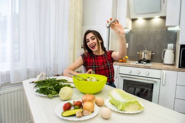 Genç kadın sebzeli salata hazırlıyor. Daha lezzetli olsun diye tuz ve biber ekliyor..