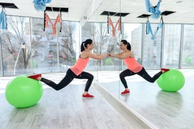 Spor salonundaki kadın, fitball 'la egzersiz yapıyor.