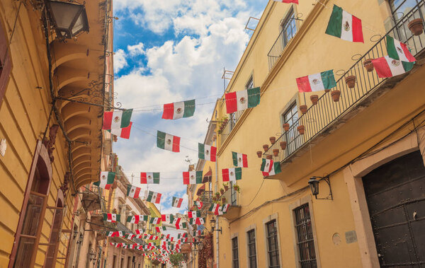 097 09 2025 Guanajuato Mexico Charming balconies with Mexican flags in the alleys of Guanajuato, Mexico, showcasing vibrant architecture, cultural identity, and festive heritage.