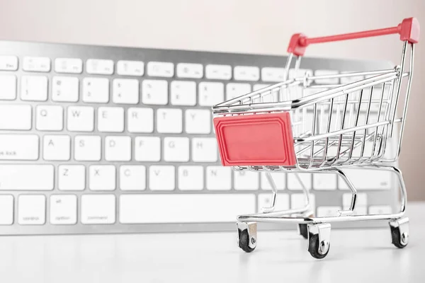 Shopping cart with white keyboard on background.