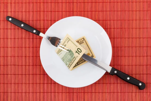 Money on plate with fork and knife. Business and financial concept