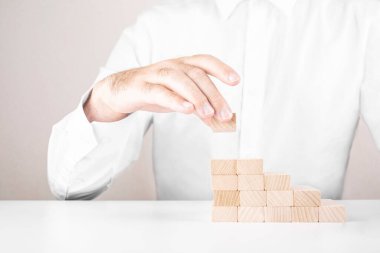 İşadamı tahta bloklardan merdiven yapıyor. İş büyümesi ve başarı kavramı
