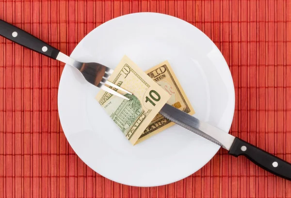 Money on plate with fork and knife. Business and financial concept