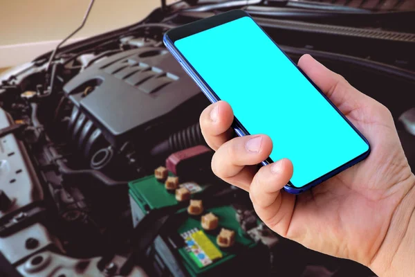 Servis, bakım konsepti için motorun bulanık arka planına sahip boş ekran akıllı telefonu elle tut