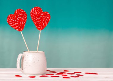 Sevgililer günü arka plan. İki kalp lolipop mavi bir arka plan ve beyaz masa arka plan üzerinde küçük kalpleri bir saçılma beyaz bir fincan şeklinde. Sevgililer günü veya düğün günü için kavram