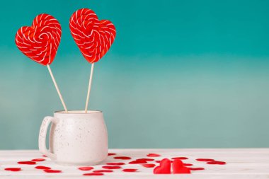 Sevgililer günü arka plan. İki kalp lolipop mavi bir arka plan ve beyaz masa arka plan üzerinde küçük kalpleri bir saçılma beyaz bir fincan şeklinde. Sevgililer günü veya düğün günü için kavram
