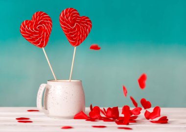 Sevgililer günü arka plan. Mavi bir arka plan üzerinde beyaz bir fincan ve tablo beyaz zemin üzerine düşen küçük kalpler kalp şeklinde iki lolipop. Sevgililer günü veya düğün günü için kavram