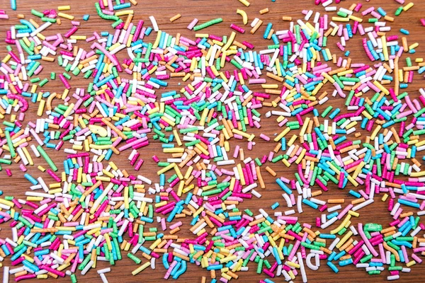 Color sprinkling. Sugar sprinkle, decoration for cake and bakery, a lot of sprinkles in a bucket on wooden board background