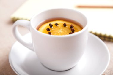 Bir fincan çay portakal ve karanfil yanındaki bir masada bir defter ve bir kalem bir parça ile keten masa örtüsü ile kaplı, eylemlerin listesini yaz. Planlama kavramı. Üstten görünüm, kopya alanı