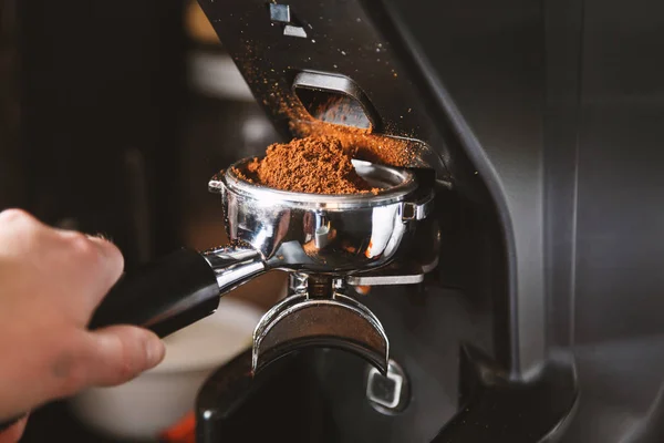 Barista kahve kahve makinesi kullanarak çekirdekleri taşlama, bir toz haline fasulye yapmak kahve değirmeni taze kavrulmuş taşlama.