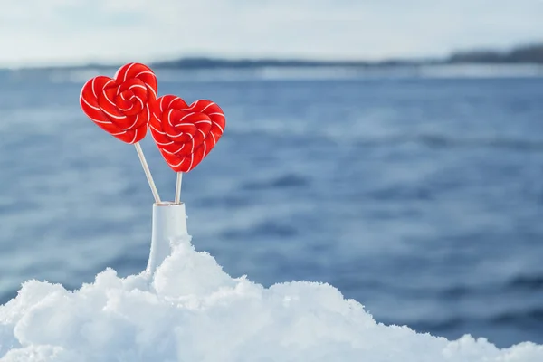 Valentine\'s day background. Candy hearts in a vase in the snow against the sea or river. Romantic date and Declaration of love on the frosty snowy shore