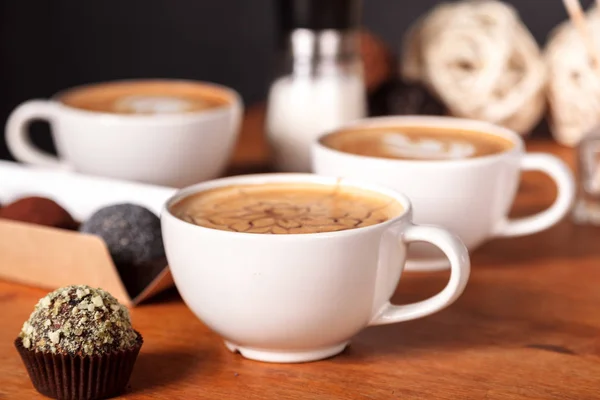 Three cups of latte coffee and small cakes on the wooden table in the cafe. Communication over a Cup of coffee with friends during a coffee break