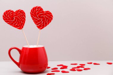 Sevgililer günü arka plan. İki kalp şeklinde şeker kırmızı bir fincan, açık gri renkli küçük kalpler bir saçılma. Tebrik kartı.