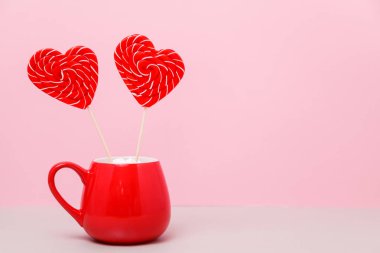 Sevgililer günü arka plan. İki kalp şeklinde şeker kırmızı bir fincan bir hafif pembe bir arka plan üzerinde. Tebrik kartı