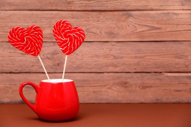 Kalp lolipop ahşap arka plan üzerinde kırmızı Sevgililer günü kupa şeklinde. Tebrik kartı