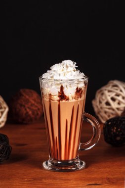 Güzel tasarlanmış latte macchiato kahve kremalı karanlık bir arka plan üzerinde yüksek bir şeffaf cam