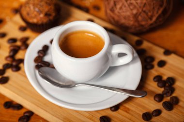 Bir fincan güzel kokulu espresso kahve ile köpük yakın çekim. Ahşap arka plan üzerinde beyaz Kupası ve kahvenin kahve dağınık