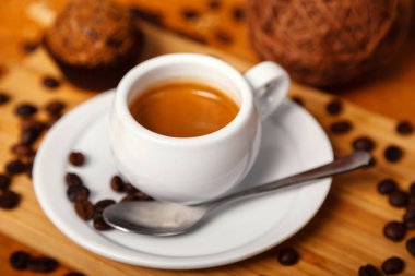 Bir fincan güzel kokulu espresso kahve ile köpük yakın çekim. Ahşap arka plan üzerinde beyaz Kupası ve kahvenin kahve dağınık