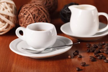 Beyaz espresso kahve fincanı, kavrulmuş kahve çekirdekleri ve süt sürahi ahşap masa arka plan üzerinde. Kahve molaları ve hizmet kahve kavramı