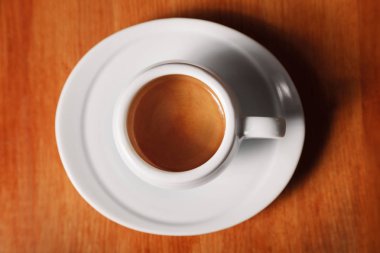 Beyaz espresso kahve fincanı lezzetli köpükle kapatın - ahşap arka plan üzerinde üstten görünüm. Kahve molaları ve hizmet kahve kavramı