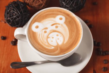 Fincan cappuccino kahve ahşap arka plan üzerinde ayı yakın çekim şeklinde bir latte sanat desenli beyaz. Bir kafede kahve yapma kavramı