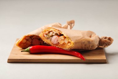 Kahve ve Shawarma sosis, patates, salatalık ve sosu bir ahşap tahta üzerinde gri bir arka plan üzerinde silindir Mini değirmenler