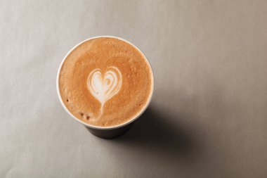 Kağıt bardak latte veya kapuçino desenli kalp latte sanat üzerinde gri bir arka plan ile. Kahve, kahve almaya