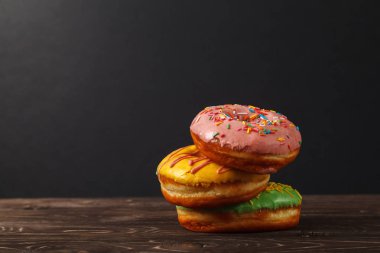 Siyah zemin ahşap bir masa üzerinde üç renkli çörekler. Fırın menü tasarım konsepti. Hanuka arka plan.