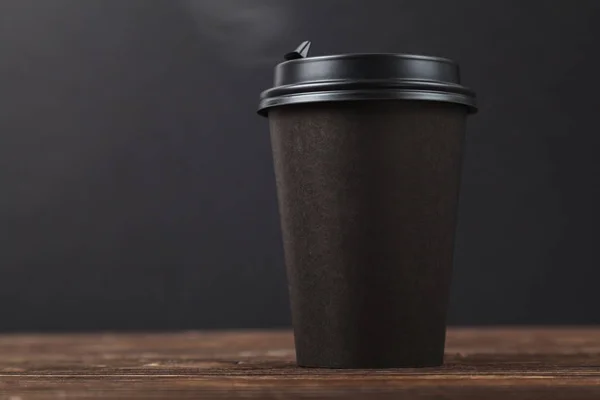 Siyah arka plan, sıcak paket kahve ahşap bir masa üzerinde. Cafe menü tasarım konsepti