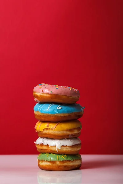 Çörek çok renkli sır içinde birbirinin üstüne kırmızı bir arka plan üzerinde kopya alanı yığılmış. Fırın reklam kavramı Stok Fotoğraf