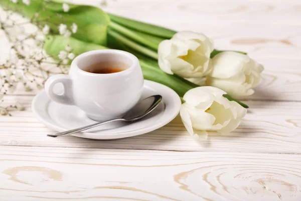 Spring tulips and coffee on a white wooden background close-up. Mother's day background, women's day, morning Birthday