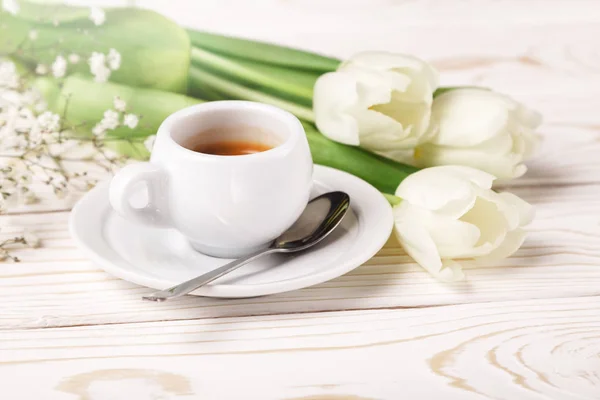Spring tulips and coffee on a white wooden background close-up. Mother\'s day background, women\'s day, morning Birthday