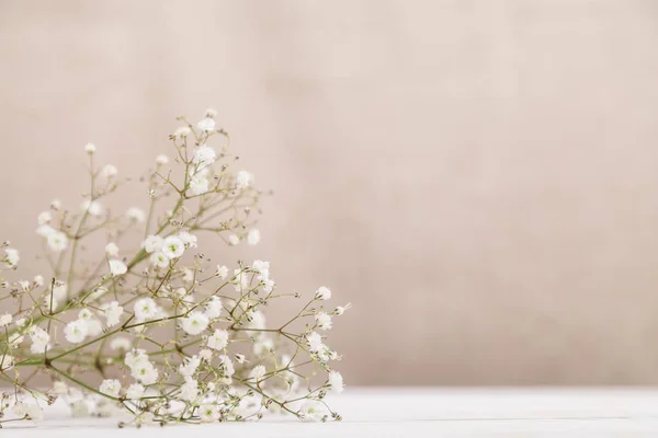 Pequenas flores brancas gypsophila na mesa de madeira no fundo bege pastel pálido. Conceito de estilo de vida mínimo. Espaço de cópia — Fotografia de Stock