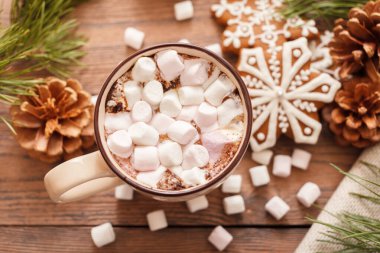 Bej rengi bir fincan geleneksel Noel sıcak çikolatası ya da şekerli kakao. Tahta arka planda Noel zencefilli ekmeği