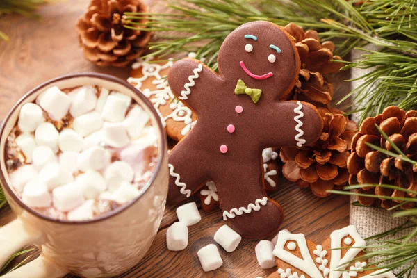 Zencefilli adam ve marşmelovlu sıcak çikolata, Noel ağacının arka planında, ahşap bir masada. - Stok İmaj
