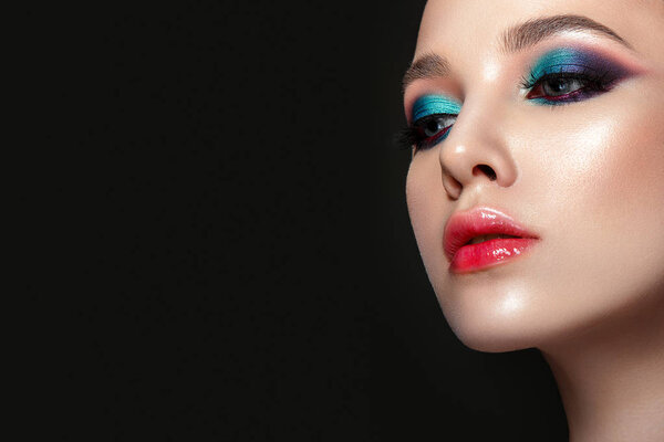 Beautiful woman portrait with bright colorful make up on black background.