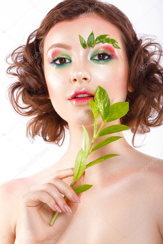 Beautiful woman portrait with colorful eyeshadows, spring colors, plant in hand