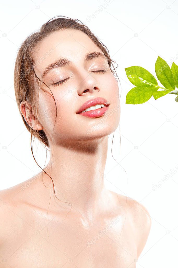 Beautiful woman portrait with fresh wet skin and green plant.