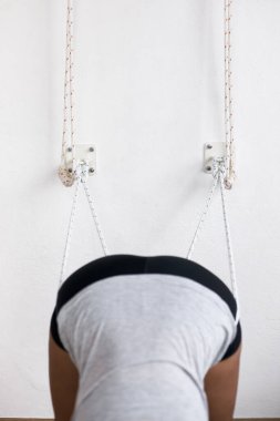 Stüdyoda duvar ipleri kullanarak yoga yapan kadın, sanırım Padangusthasana.