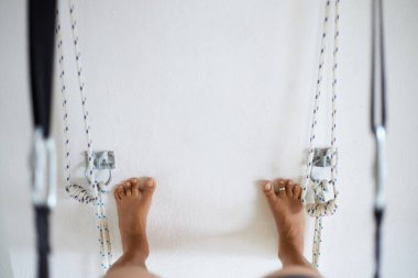 Stüdyoda duvar ipleri kullanarak yoga yapan kadın, sanırım Padangusthasana.