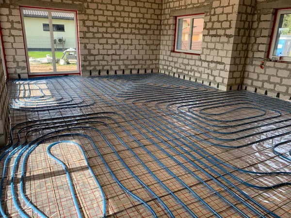 Underfloor heating and cooling installation in brick house, blue pipes for floor heating at the house construction, warm floor during the winter