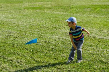 Bir mavi oyuncak uçak park adlı bir güneşli yaz gününde oynayan çocuk