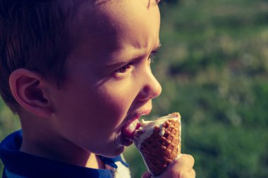eriyen bir dondurma bir bunaltıcı sıcak yaz gününde zevk 3 yaşında bir beyaz çocuk. Yeşil yaz ağaç arka planda