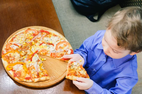 Sevimli küçük beyaz çocuk pizza, yemek tarifi. Bir partiye pizza tarafından bir ısırık alarak aç çocuk.