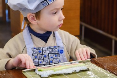 Yemek, geleneksel sushi hazırlanması alır. Çocuk aşçı olarak giyinmiş.