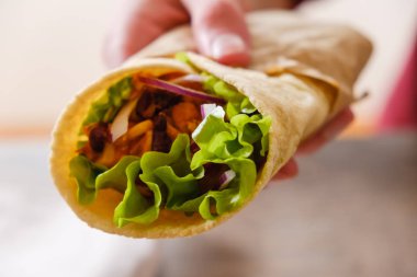 Meksika dürümü, tavuk, sebze, biber ve fasulye. Burrithos elinde yemek tutuyor. Beyaz arka planda sokak yemekleri