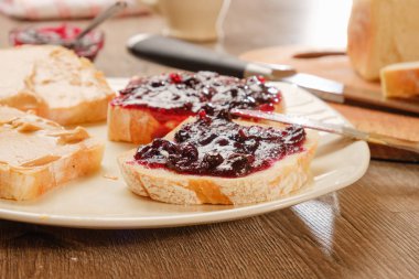 Reçelli fıstık ezmeli sandviç. Kesme tahtası, mutfak bıçağı..